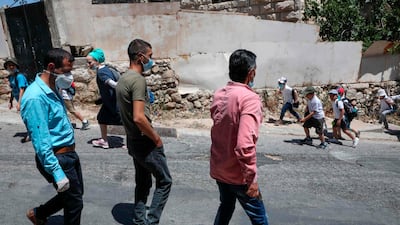 Palestinian men walk past a group of Israeli settlers as they walk home on al-Shuhada street in the H2 area of the city of Hebron, in the occupied West Bank. AFP