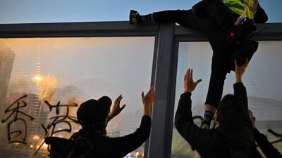People help a first aid volunteer climb a noise barrier to avoid police following a pro-democracy march from the Tsim Sha Tsui district to Hung Hom in Hong Kong. AFP