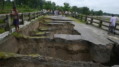 Indian people look at a bridge damaged by torrential rain on the outskirts of Siliguri. Diptendu Dutta / AFP Photo
