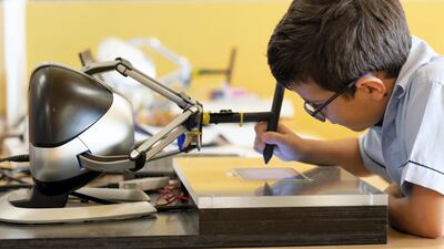 A Cranleigh Abu Dhabi pupil uses a robot to steady his hand during a new trial to improve handwriting. Courtesy: Cranleigh