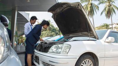 Staff from a private insurance company inspect a vehicle for insurance coverage in Yangon. Romeo Gacad / AFP