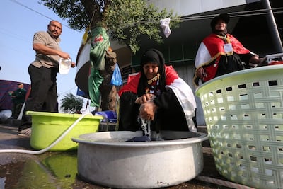 Iraqi women volunteer to wash the clothes of protesters by hand in Tahrir Square. AFP
