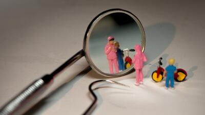 A girl checks her reflection in the mirror of a dentist's tool. Courtesy Omar Maree Humaid