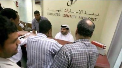 Men take a number and wait in line, often for hours, to apply for their identification card at the Emirates Identity Authority.