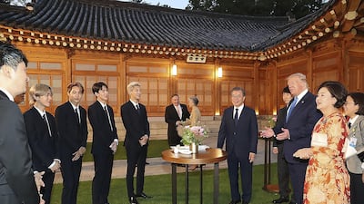 US President Donald Trump talks with South Korean boy band Exo as South Korean President Moon Jae-in stands during a dinner at the presidential Blue House on June 29, 2019 in Seoul, South Korea. Photo by South Korean Presidential Blue House via Getty Images
