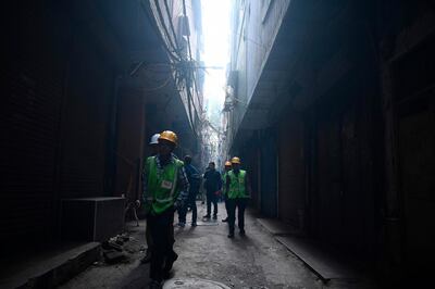 Workers walk on a street near a factory site where a large fire broke out a day before, in the Anaj Mandi area of New Delhi, killing at least 43 people. AFP