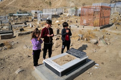 Ada Ahmadi stands with her cousins as they pray by the grave of their relative Farzad, who was a victim of a US drone strike that killed 10 civilians, including seven children, in Kabul, Afghanistan, on November 7, 2021. Reuters