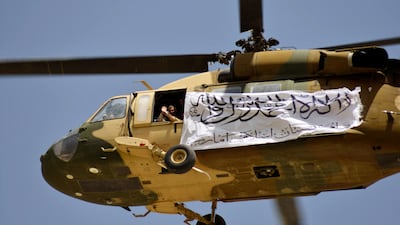 A helicopter displaying a Taliban flag flies above supporters gathered to celebrate the withdrawal of all US troops from Afghanistan, in Kandahar. AFP
