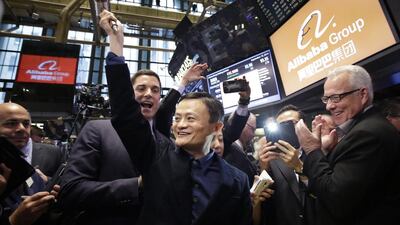 Jack Ma, center, founder of Alibaba, raises a ceremonial mallet before striking a bell during the company’s IPO at the New York Stock Exchange. Mark Lennihan / AP Photo