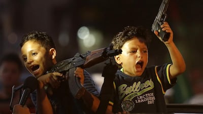 Children hold up guns (one with an empty magazine) from a car as Palestinians gather in the streets to celebrate. Mohammed Abed/ AFP Photo