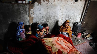 An Afghan family warm themselves around a traditional “sandali” stove. Aref Karimi / AFP Photo