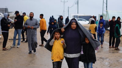 Displaced Palestinians, who fled their houses due to Israeli strikes, walk in heavy rain. Reuters