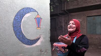 An Egyptian 'Mosahrati', or late night waker, bangs her drums and calls out to the Muslim faithful around the Maadi neighbourhood before dawn in Cairo, Egypt. EPA