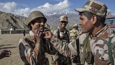 An Indian security force soldier has his helmet adjusted by another as they wait to leave on election duty from a central collection point to head to secure polling stations in Leh, Ladakh, India.