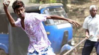 A protestor throws a rock at supporters of former army commander General Sarath Fonseka during a demonstration against his arrest in Colombo, on Wednesday, February 10, 2010.