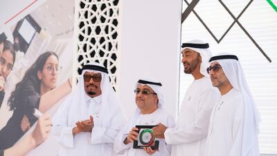 Sheikh Mohamed bin Zayed, second right, presents an award for Marwan Al Rostamani (second left) and Hassan Al Rostamani (right) on behalf of Al Rostamani Group for participating in Sandooq Al Watan. Ryan Carter for the Ministry of Presidential Affairs