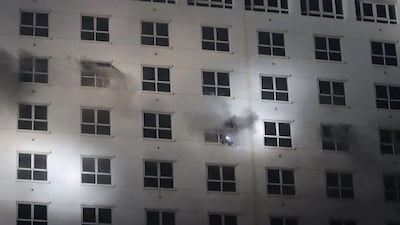 People flash lights from a window during the fire. AFP