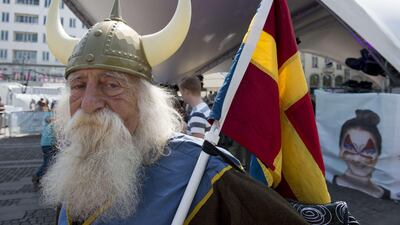 A Malmo resident dressed in a viking costume holds a composite "scandinavian" flag at a Eurovision public viewing area in downtown Malmo ahead of the final. John MacDoughall / AFP