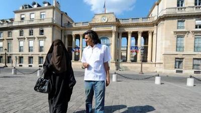 Hind, a Niqab veiled woman, and real estate magnate Rachid Nekkaz, who supports Muslim women fined for wearing the burka or niqab on the street, walk in front of the French National Assembly during a symbolic protest against France's ban on wearing full-face niqab veils in public, on April 20, 2011 in Paris.