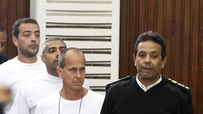 epa04148405 Australian journalist Peter Greste (C) and other co-defendants are accompanied by police officer outside court's cage during their trial for allegedly supporting a terrorist group and spreading false information, in Cairo, Egypt, 31 March 2014. Judge Mohammed Nagui, who is trying three Al-Jazeera journalists and five co-defendants on terror charges in Egypt, called them out of the defendant's cage on 31 March 2014 to hear individual requests. The trial was adjourned until 10 April. A total of 20 defendants in the case are charged with harming Egypt's national interests by spreading false news and assisting or belonging to a terrorist organization, but 12 are being tried in absentia. EPA/KHALED ELFIQI