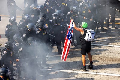 A demonstrator holds a US flag opposite California Highway Patrol officers. Reuters