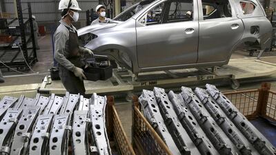 Workers stand near a vehicle frame at an assembly line of Datsun Go+. Beawiharta / Reuters