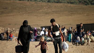 Syrians walk carrying their belongings on August 22, 2017 after crossing the Syria-Jordan border near the town of Nasib as they return to their homes following a US-Russia ceasefire brokered in three southern provinces. Mohamad Abazeed / AFP