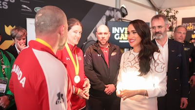 Meghan wears a white Valentino dress as she chats with members of the Canadian Invictus Team. Getty Images