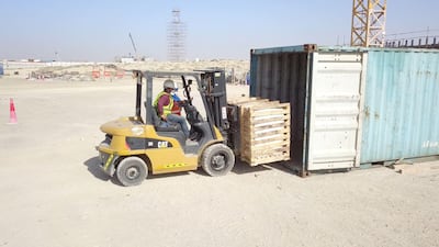 Workers deposit wooden crates with stone carvings across the Hindu temple site in Abu Mureikha area.