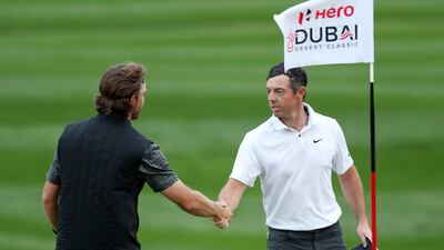 Tommy Fleetwood and Rory McIlroy of Northern Ireland shake hands on the 7th green as play is suspended. Getty