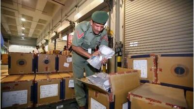 A police officer in the department of airport security works at the front line of border protection, checking the contents of boxes of shipped goods at Cargo Village in Dubai. Randi Sokoloff / The National