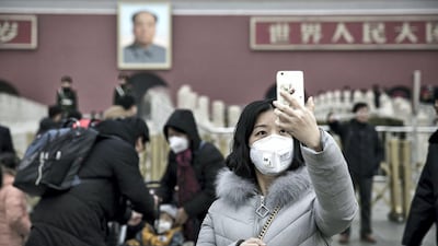 A young woman wearing a face mask takes a selfie photograph in front of the Tienanmen Gate in Beijing, China. Bloomberg