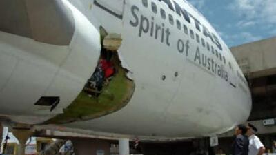 The Qantas pilot Capt John Francis Bartels, right, looks at the hole of the Melbourne-bound Boeing 747 after it made an emergency landing at the international airport in Manila.