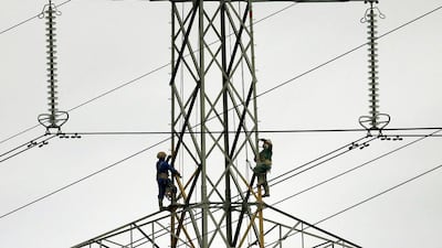 Workers paint an electricity pylon near Lymm, northern England February 18, 2015. Most British energy consumers who have not switched supplier and/or tariff have missed out on saving up to £234 (US$360) a year a watchdog’s report on competition in the industry showed on Wednesday. Phil Noble / Reuters