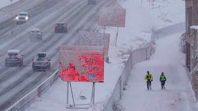 Runners negotiate snow-covered paths along Interstate 80 in Salt Lake City, Utah. AP