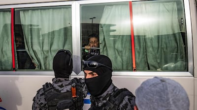 A child looks through the window of a bus at security officers during the handover of 34 orphaned children of suspected ISIS fighters by Syrian Kurdish officials to a Russian delegation in the city of Qamishli, north-east Syria. AFP