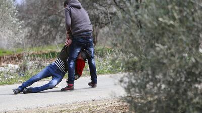 A Palestinian protester helps another who was injured on February 15, 2014, during clashes with Israeli forces near the West Bank village of Tourah, west of Jenin. Dozens of Palestinians held a march to protest against the Palestinian-Israeli peace talks and US Secretary of State John Kerry’s peace efforts. Mohammed Ballas / AP photo