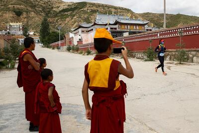 Monks wave to a participant of the Super Salmon ultra-marathon near the Longyangxia Reservoir. Reuters