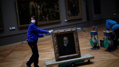 A worker transports a painting called 'Portrait of Antonio de Covarrubias y Leiva' by Spanish painter El Greco in the Louvre on February 9, 2021. AP