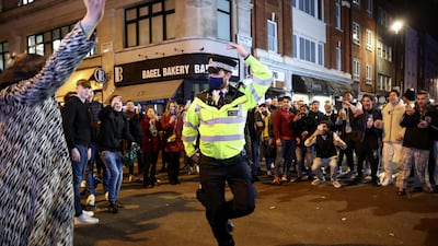 A policeman dances with people partying along a street in Soho, Central London, as Britain eases coronavirus restrictions. Reuters