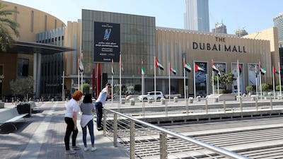A visitor has their picture taken outside Dubai Mall. Tourists can reclaim VAT on retail purchases made in stores marked with 'tax-free' stickers. Chris Whiteoak / The National