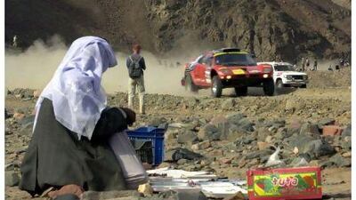 An Egyptian vendor watches German driver Jutta Kleinschmidt who races through the mountains of Wadi Masdud in South Sainai, Egypt, in January 2003 during a special stage a day before the last stage of the Dakar Rally. AP Photo