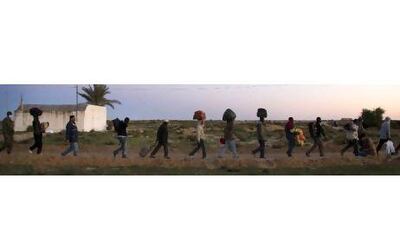 West African migrants walk towards their tents at a UN camp near Ras Ajdir. Refugees are eating meals donated by local restaurants with many sleeping in schools and youth hostels.