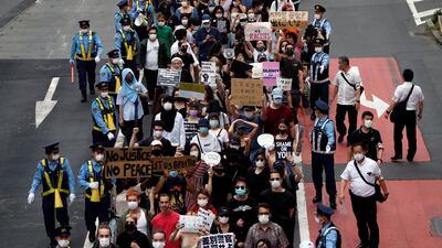People wearing masks hold placards during a protest march over the alleged police abuse of a Turkish man in Tokyo. Reuters