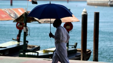 A man takes shade under an umbrella on sweltering day in Bur Dubai. Chris Whiteoak / The National