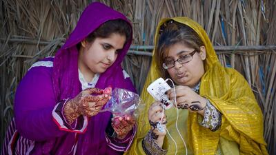 Anoud Al Jasmi, 20, on the left, and Bedour Al Jasmi, 18 browse photos on a mobile phone while camping in Dibba. The sisters relax there by day and then sleep at a hotel near by at night.