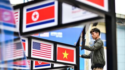 A man fixes an electric line next to pictures of Vietnam, US and North Korean national flags. AFP