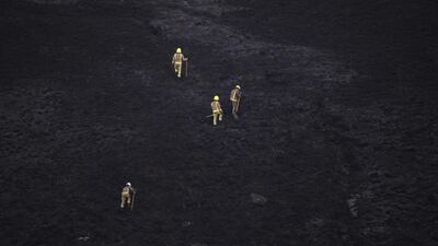 Firefighters walk across burnt moorland as they tackle a blaze above Marsden. AFP