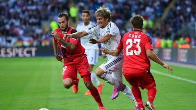 Real Madrid’s Fabio Coentrao, centre, vies with Sevilla’s Aleix Vidal, left, during a Uefa Super Cup football match at Cardiff City Stadium in Cardiff, south Wales on August 12, 2014. AFP PHOTO / CARL COURT
