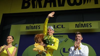 UAE Team Emirates rider Tadej Pogacar celebrates on the podium with the overall leader's yellow jersey after Stage 16. AFP